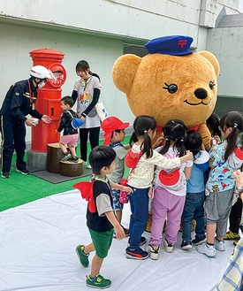 「ぽすくま」が登場し、触れ合いを楽しむ園児たち（提供写真）