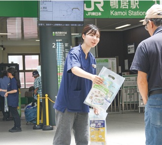 鴨居駅改札口前で飲料などを配布し、熱中症予防を呼び掛ける学生たち