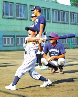 大学生の指導を受け楽しそうにバットを振る児童