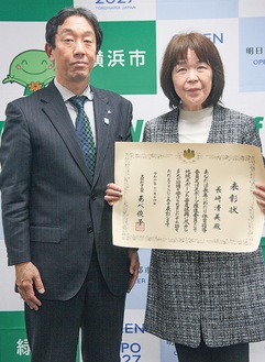 表彰を受けた長崎さん（右）と表彰状を手渡した佐藤区長