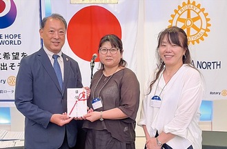 花房会長（中央）に目録を手渡す森会長。右はスマイリーの堤盟子副会長