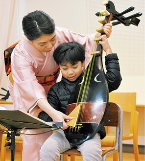 琵琶の弾き方を教わる子ども