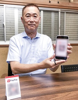 スマホの画面を見せる豊岡会長