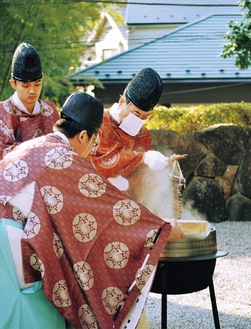 大釜から葭の筒を引き上げる石川宮司