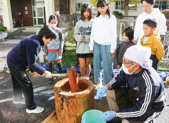 他学年の児童に見守られ餅つきに挑戦