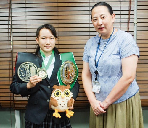 チャンピオンベルトと、植木区長から贈られた「せやまる」のぬいぐるみを持つ山下さん