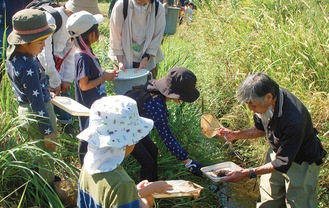 生き物を子どもたちに見せる宮島代表（右）