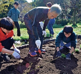 協力しながら花を植える参加者ら