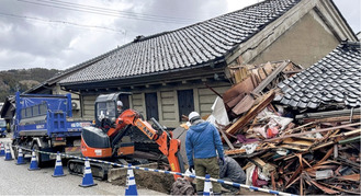 倒壊建物の近くで水道復旧にあたる作業員