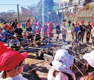 焚き上げに使った火で餅を焼く南本宿小学校の児童ら