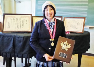 沢山の賞状に囲まれて笑顔の漆原さん