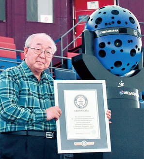 プラネタリウム投影機と公式認定証を持つ的川館長（はまぎん こども宇宙科学館提供）