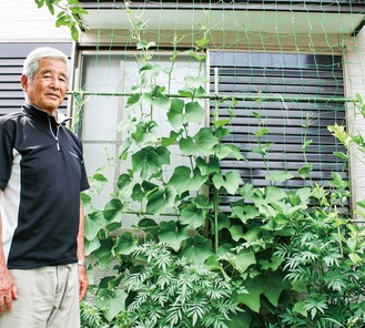 自宅に設置した緑のカーテンを前にする吉澤さん