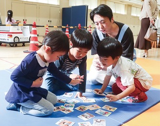 学生と防災かるたで遊ぶ子どもたち