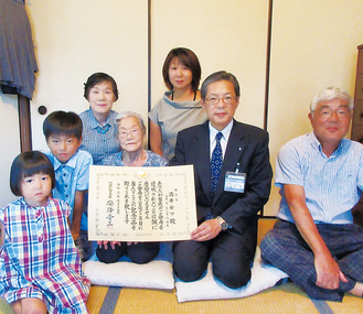 猪俣区長から祝状を手渡された酒井さん（中央）