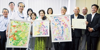 寄贈された絵画を手にする贈呈式参加者