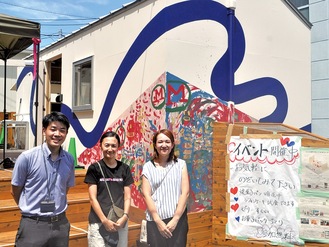 タイニーハウスの前に立つ同社の高辻さん、開設メンバーの高宮理紗さんと神保さん（左から）