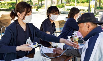 血圧を測定する来場者（右）