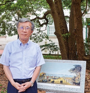 横浜開港の歴史を見守ってきたたまくすの木の下にある「横浜上陸の図」のパネル前で西川館長