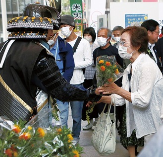 紅花の花束を受け取る来場者