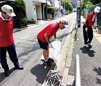 たばこの吸殻などを拾う職員＝同センター提供