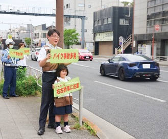 運転手に注意を呼び掛ける住民と警察官