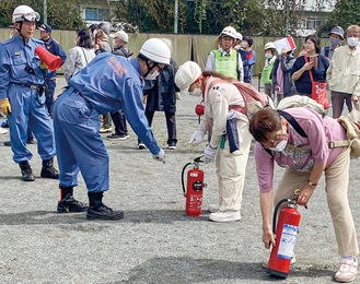 消火器の取扱方法を学ぶ参加者