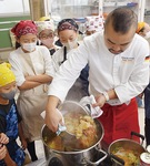 炒めた野菜を煮込む小林氏