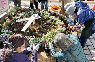 花壇に堆肥を撒き、花を植える参加者（区提供）