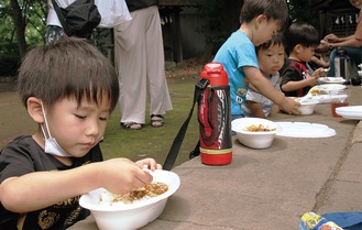 神社でカレーをほおばる子どもたち