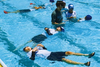 ペットボトルを抱えて水に浮く練習をする児童