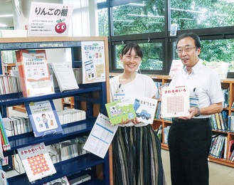 りんごの棚の横で笑顔の小室館長（右）と職員