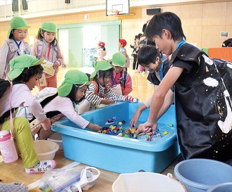 ペットボトルでできた金魚すくいを楽しむ園児