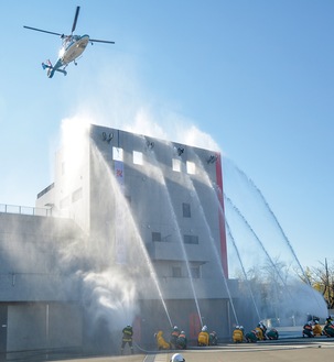 一斉放水のなか祝賀飛行する消防ヘリコプター