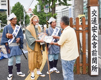 「宮前関所」前で啓発物を渡す杉田進会長扮する水戸黄門（左から２番目）