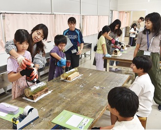 電動ドリルを使って竹灯籠を作る児童たち