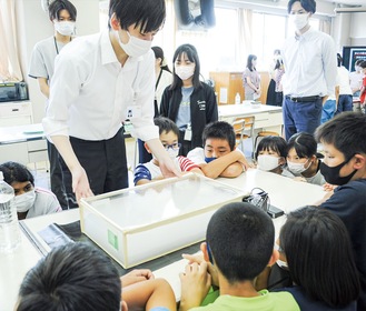 室内を模した実験装置を真剣に見つめる児童ら