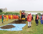 雨の中の訓練で土砂を撤去する建友会メンバー＝多摩川河川敷