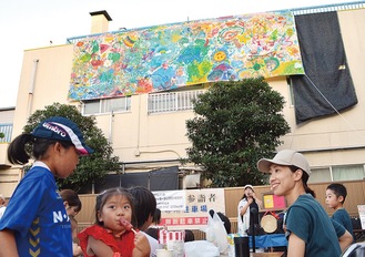 作品の下で祭りを楽しむ親子