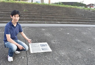 跡地で記念プレートを指さす小林さん