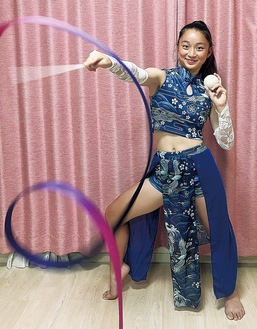 ジャズダンスの衣装でリボンを回し、左手に野球ボールを持つ力丸さん