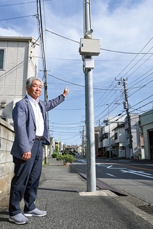 街路灯に設置された防犯カメラを指す阿部部長