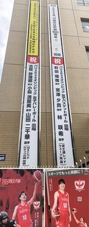 区役所に掲出された区ゆかりの選手を応援する懸垂幕（上）と、町田選手と宮澤選手の案内板