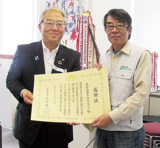 7月に市から表彰伝達を受けた小泉会長（右）