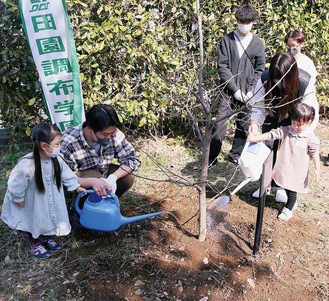 植樹した木のまわりに水をやる子どもたち