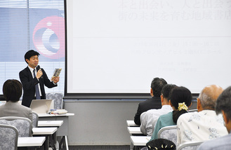 本を手に講演する北野氏