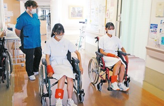 職員が見守る中、車椅子を体験する高校生