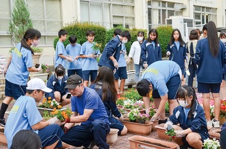 協力してプランターに花を植える生徒たち