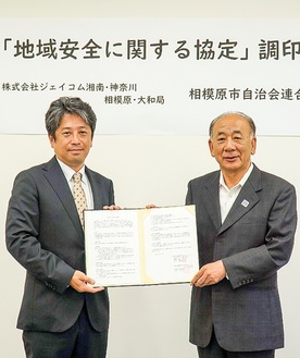 協定書を交わす竹田会長（右）と同局の加藤局長（左）21日、千代田の同局社屋で