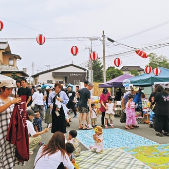 ヨーヨーつりやうちわ作り、祭り囃子、食事などを楽しむ参加者たち